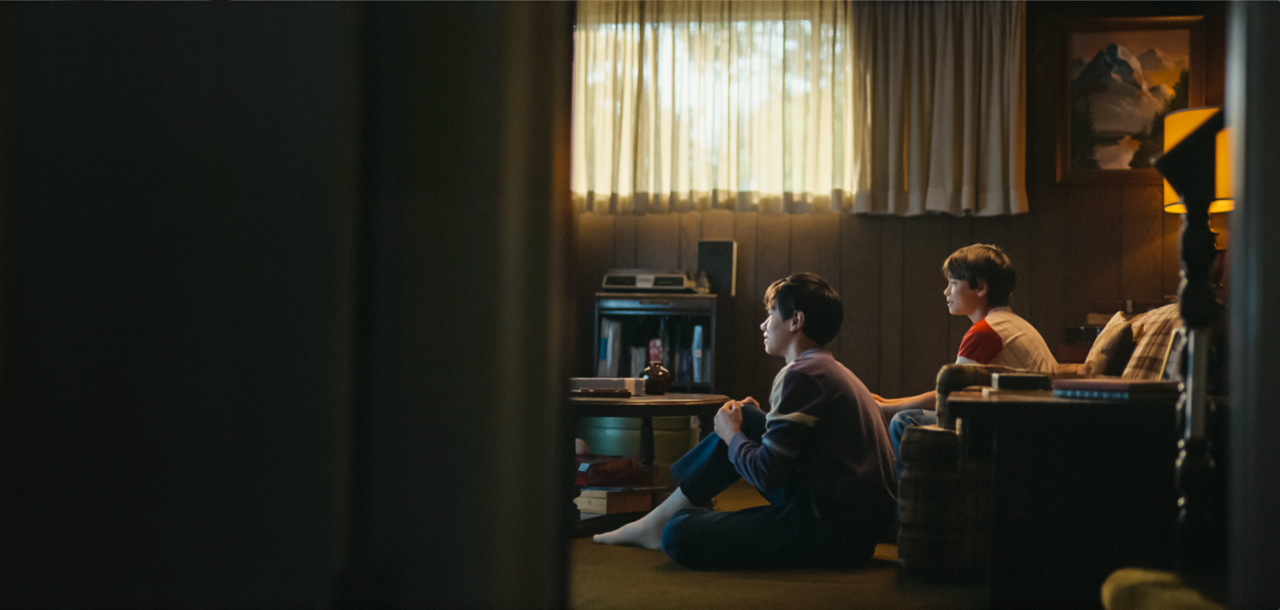 A flashback image of two young McKeever brothers attentively watching TV at home in their living room.